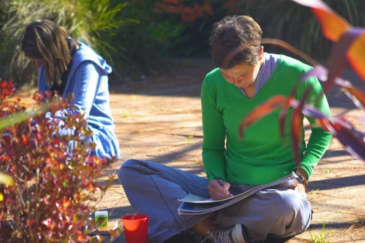 An Introduction to Art Therapy - two students sitting on the floor outside painting what the art therapy teacher has asked them to do.