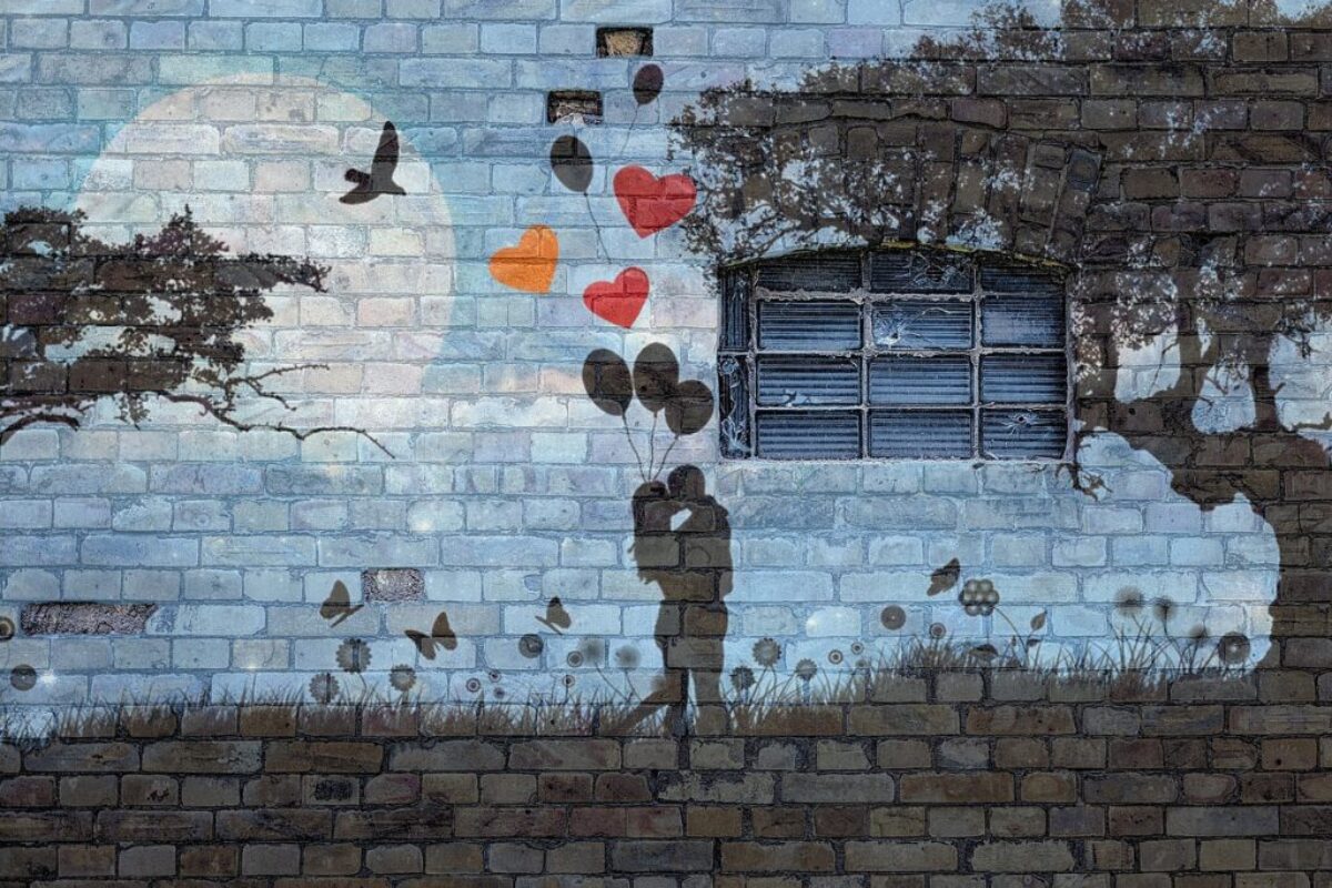 Art Therapy for Couples: Bridging the Gap in Relationship Counselling through a murial on a brick wall that shows two lovers embraced with balloons and love hears above them like in a famous painting.