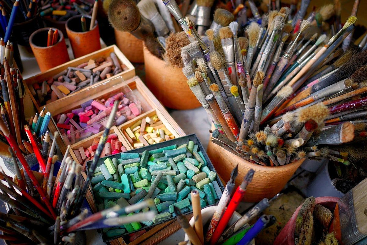 Collection of paint brushes, crayons and other art materials.