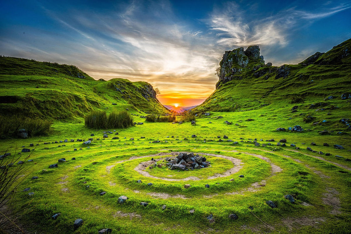 Green mountain top with a circular walking path at sunrise.
