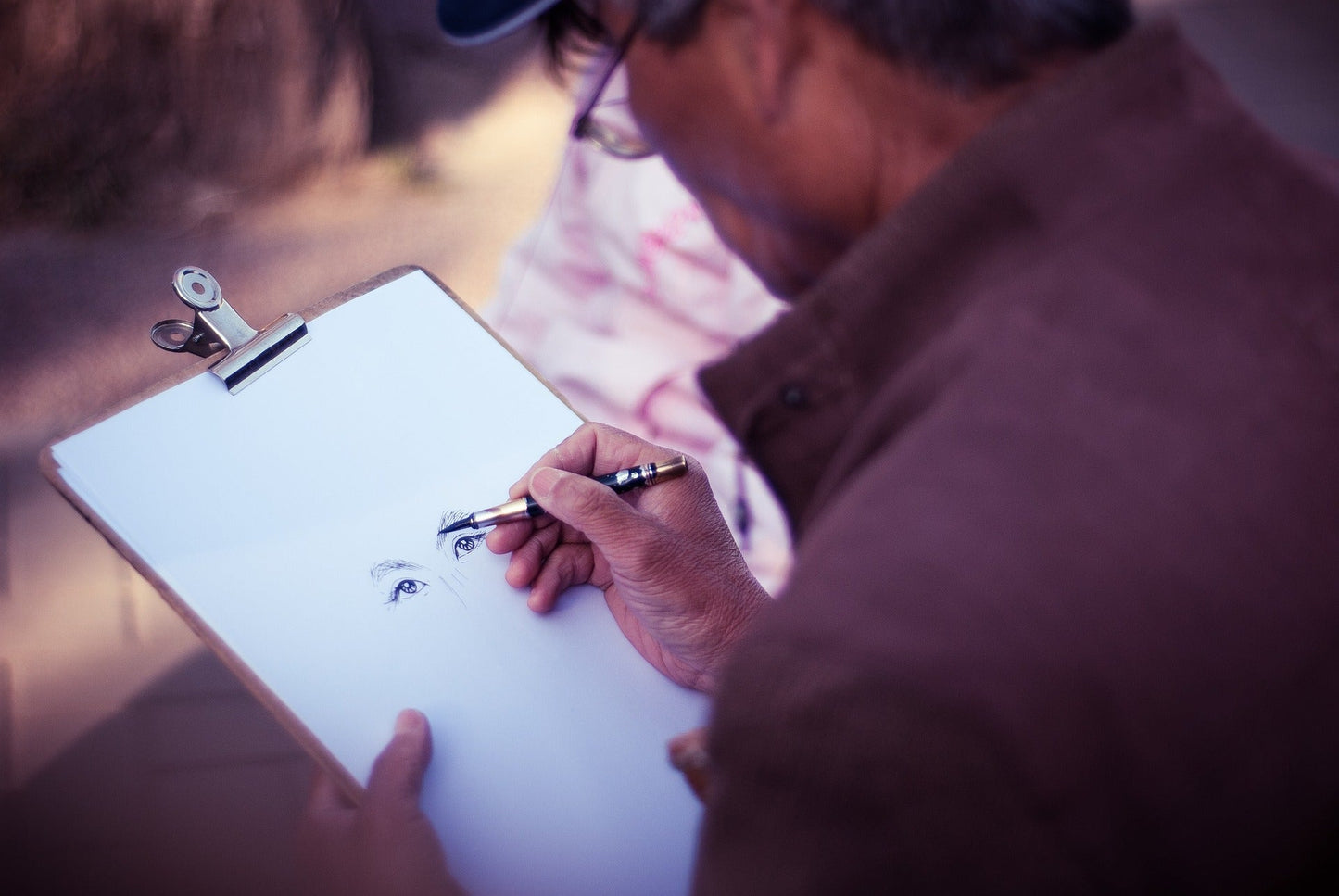 Art Therapy Benefits for the Older Adults showing an older man drawing two eyes with purpose and detail, quite skilfully.