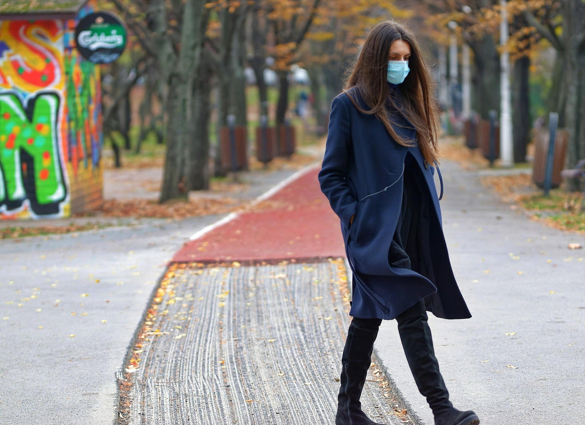 Woman with face mask going for a walk in a park.
